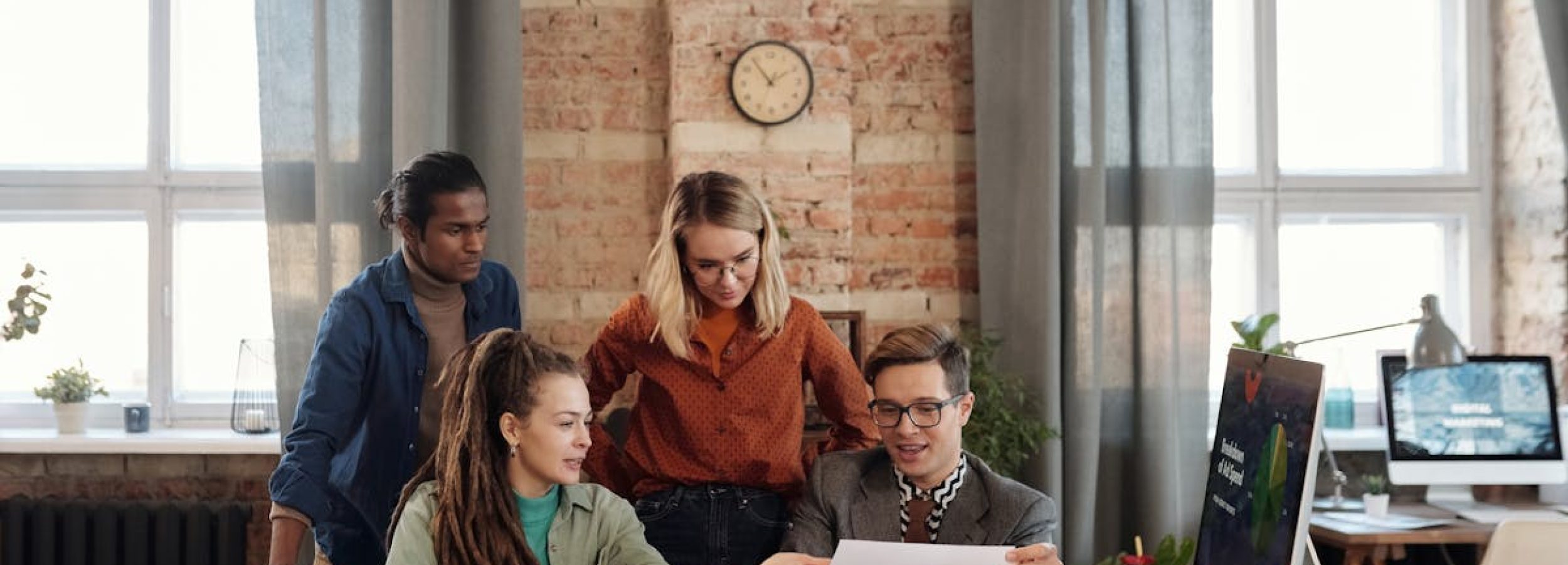 A diverse team of young professionals working on a business strategy in an urban office setting.